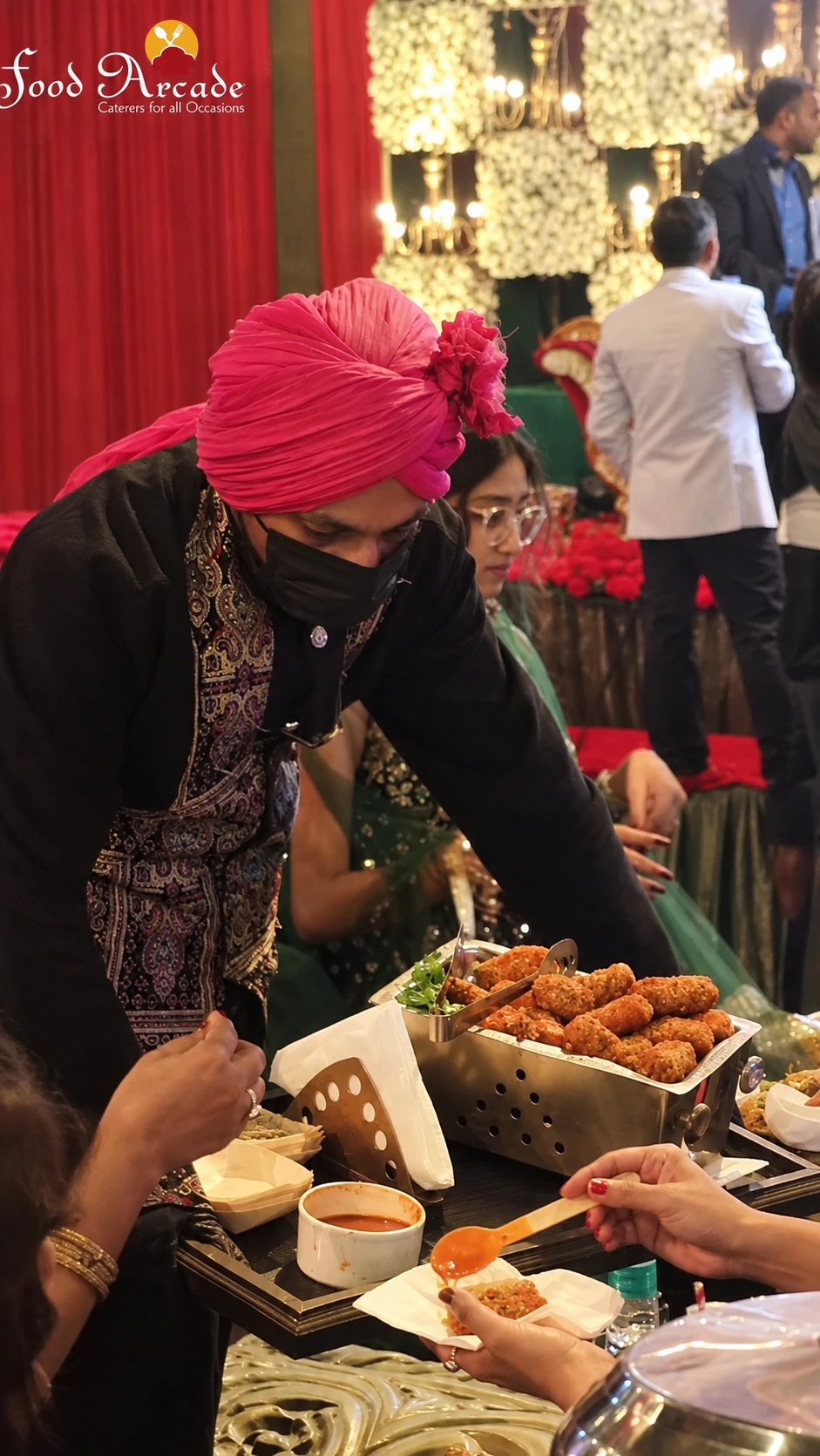 Server serving fried snacks and chutney to guests at a celebration