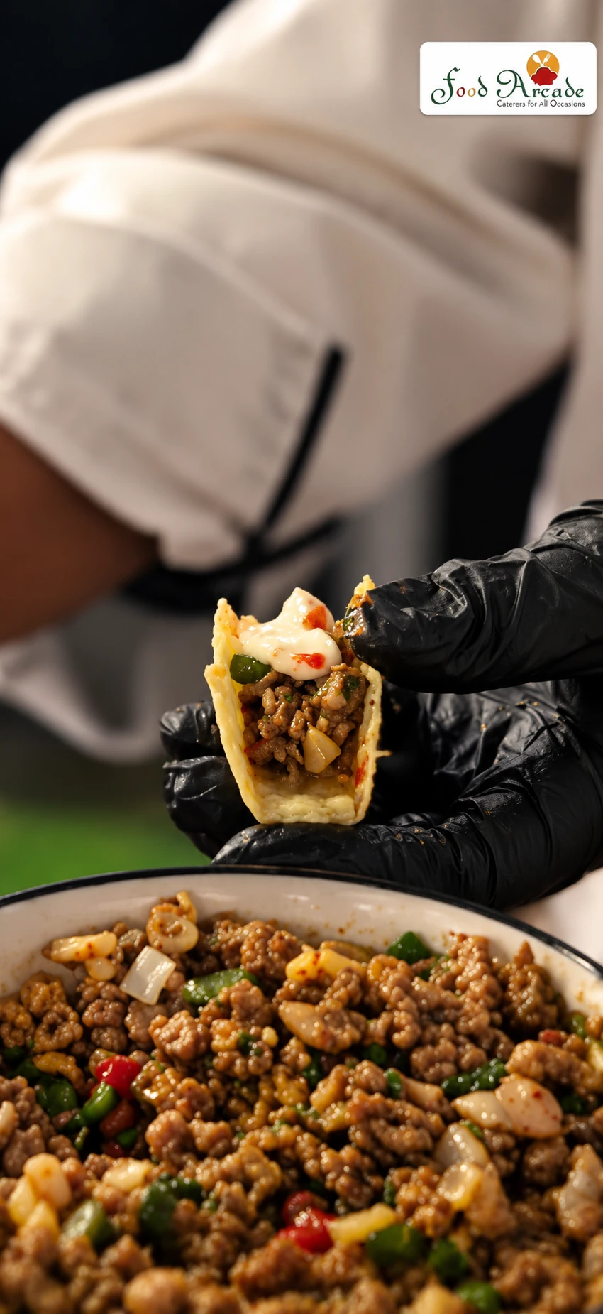 Gloved hand holding a taco shell filled with spiced mince above a bowl of the filling